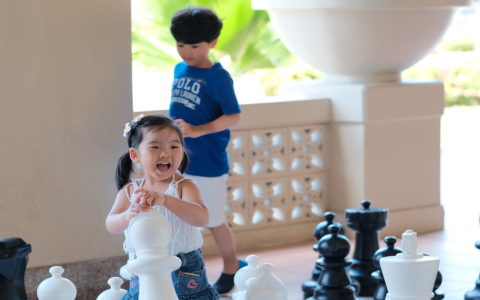 Kids are smiling and playing with oversized chess