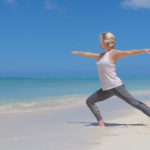 A woman is practicing Tai Chi at the beach